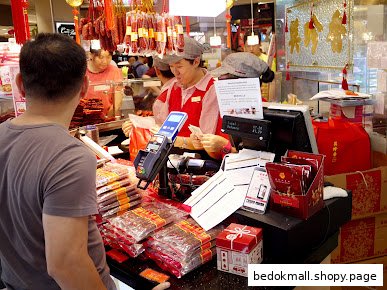 Customer at counter with staff and products in a retail shop.