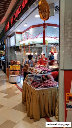 Shop interior with staff, customer, and products on display at Bee Cheng Hiang.