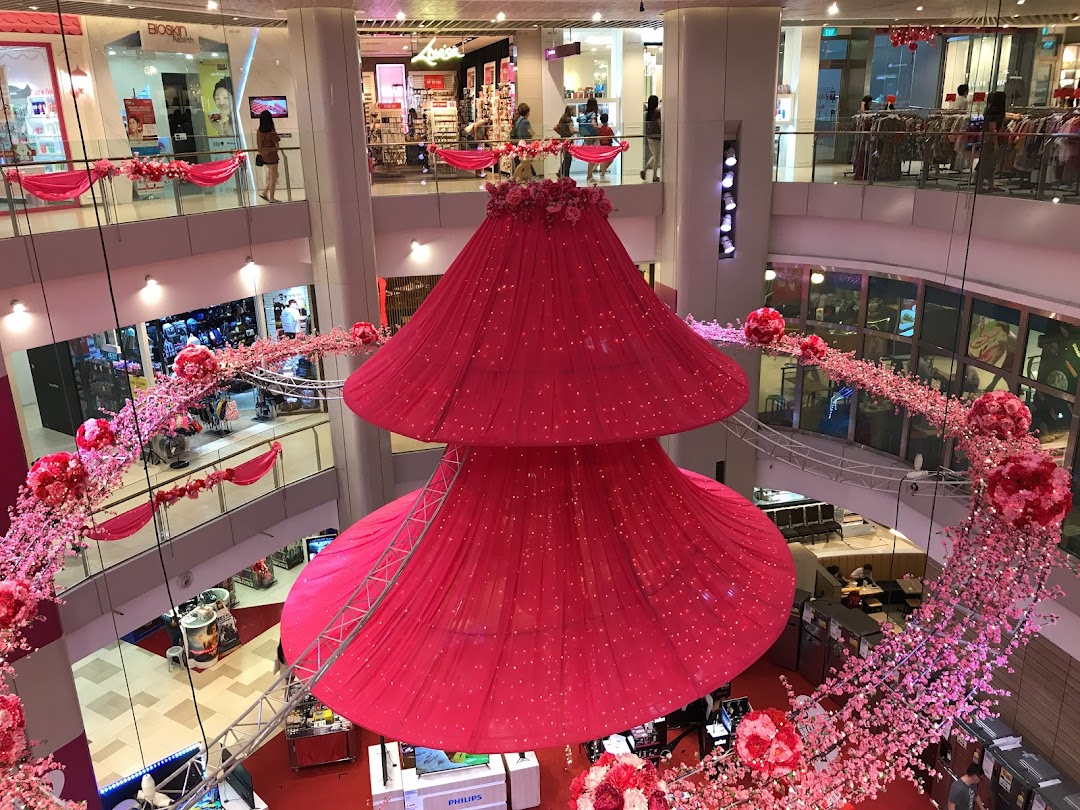 Multi-level mall interior with large pink decorations and various shops.