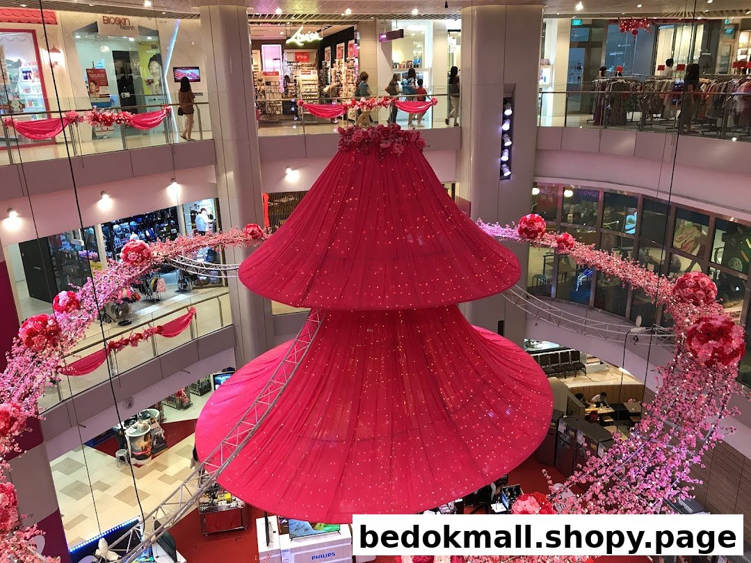 Multi-level mall interior with large pink decorations and various shops.