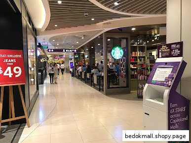 Interior view of a shopping mall corridor with a Starbucks cafe and people.