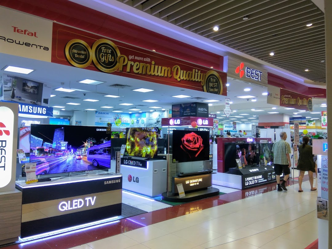 Interior of an electronics store with many TVs on display and customers.