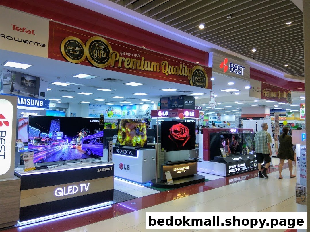 Interior of an electronics store with many TVs on display and customers.