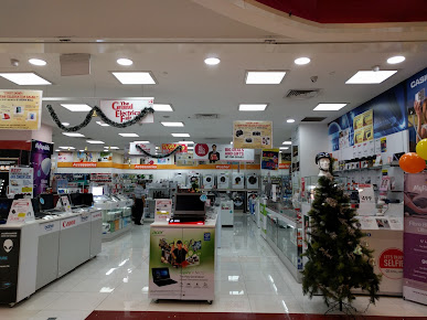 Retail interior of an electronics store with product displays and festive decor.