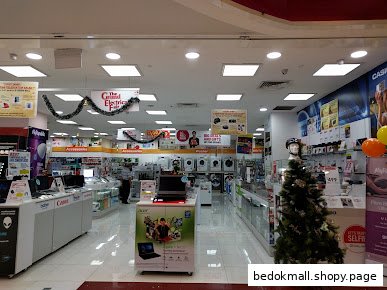 Retail interior of an electronics store with product displays and festive decor.