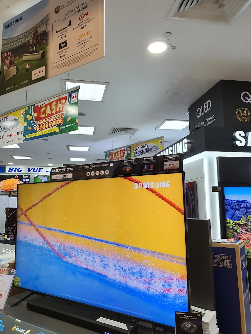 Interior view of an electronics store displaying large TVs and promotional banners.