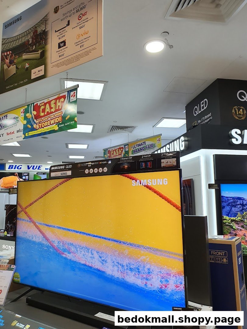 Interior view of an electronics store displaying large TVs and promotional banners.