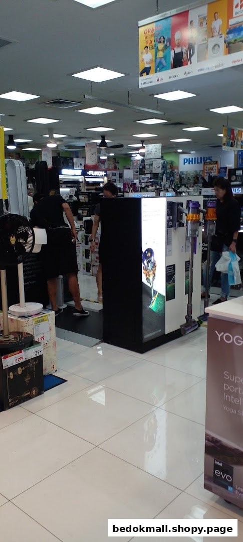 Interior view of an electronics store with customers and various products on display.