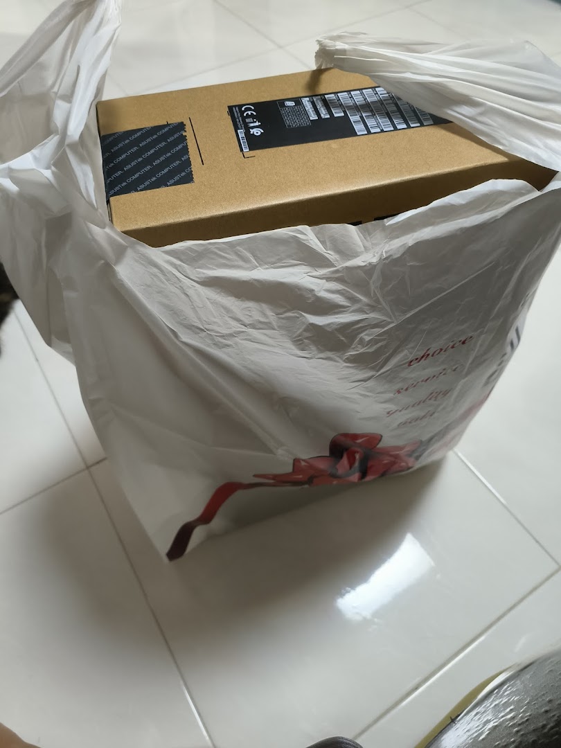 A brown product box is inside a white plastic shopping bag.