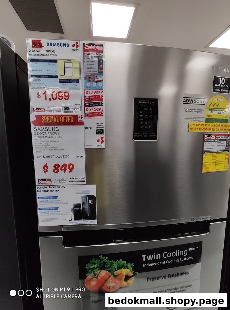 A silver Samsung refrigerator with price tags and product information on display.