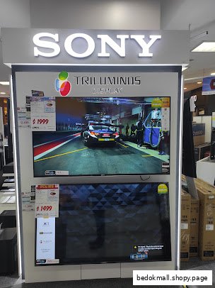 A Sony TV display stand with two televisions in a retail store interior.