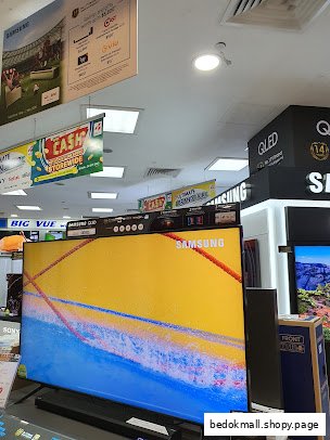 Interior view of an electronics store with large TVs and promotional banners.