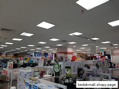 Interior view of a large electronics and home appliance store with various products on display.