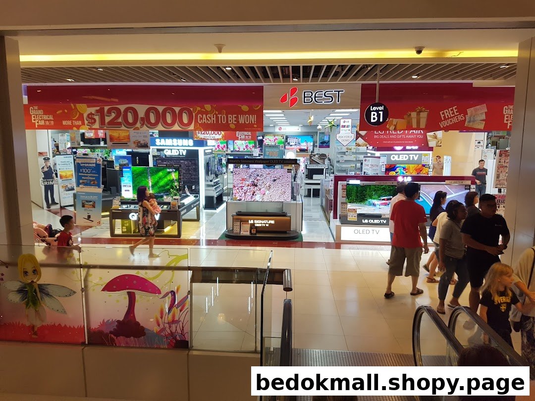 Entrance of an electronics store with TVs on display and people walking by.