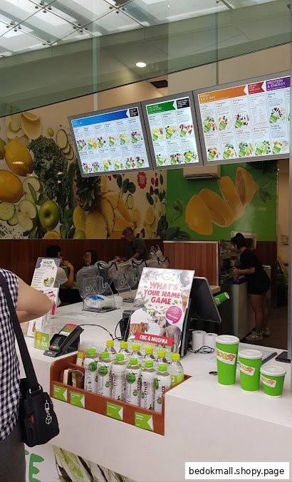Interior view of a Boost Juice counter with digital menus and customers.