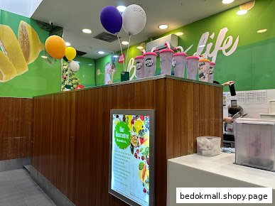 Interior view of a Boost Juice counter with merchandise, balloons, and staff.