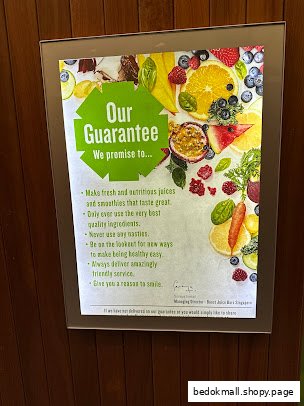 A backlit sign displaying Boost Juice's guarantee about fresh ingredients and service.