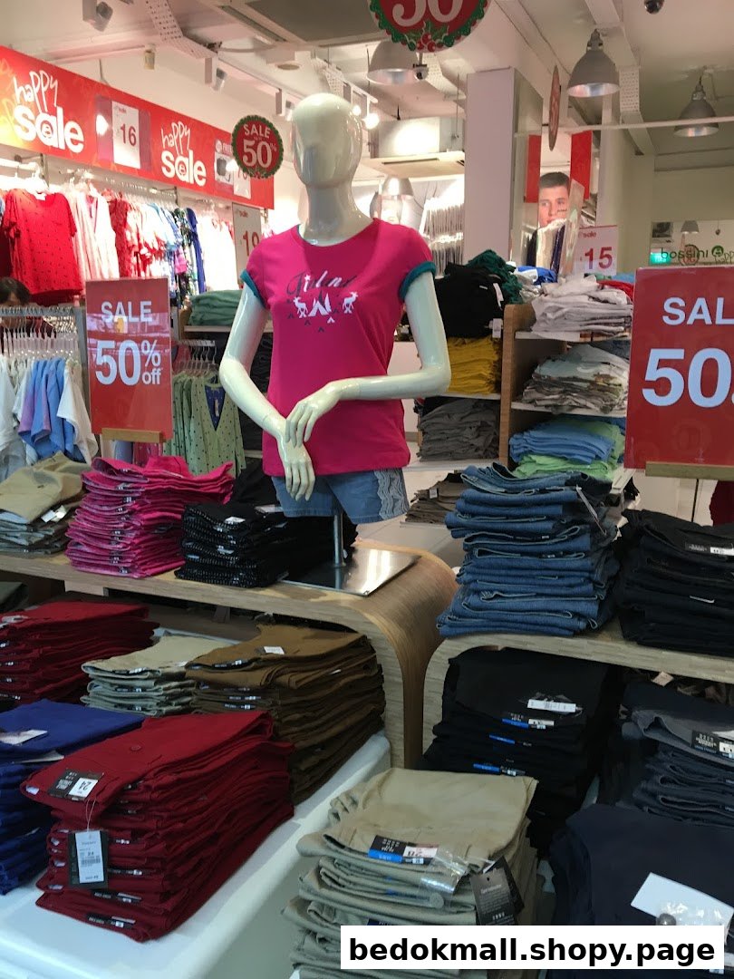 Mannequin and folded clothes on display in a retail store with sale signs.