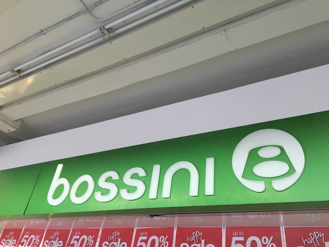 Close-up of Bossini shop sign with sale banners displayed below.