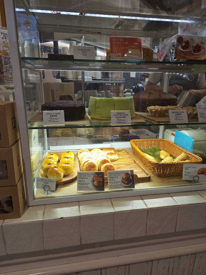 A display case filled with various cakes and pastries with price tags.