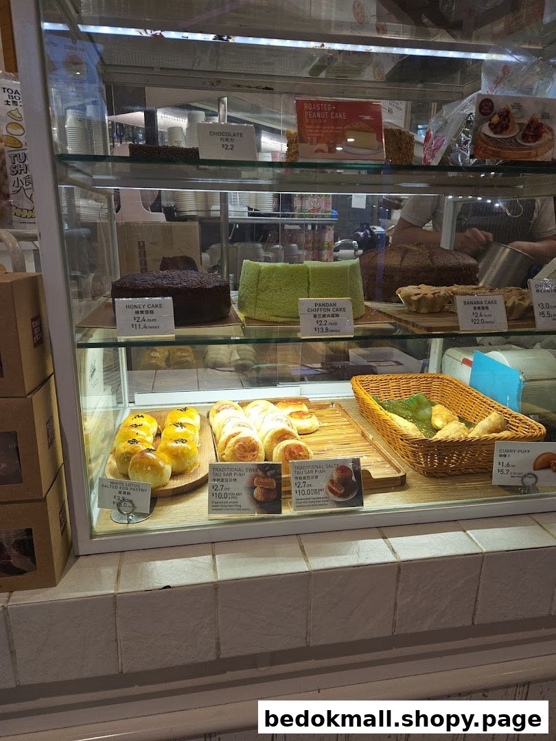 A display case filled with various cakes and pastries with price tags.