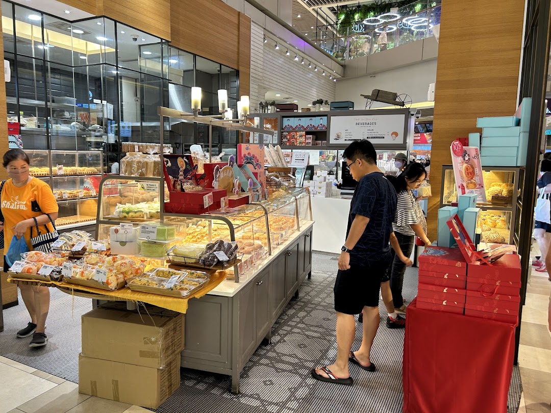 Interior view of a bakery with display cases of baked goods and customers browsing.