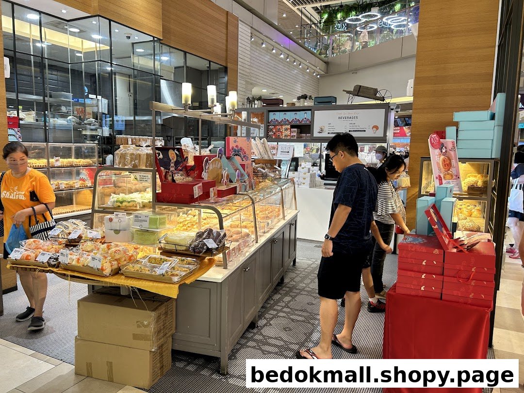 Interior view of a bakery with display cases of baked goods and customers browsing.