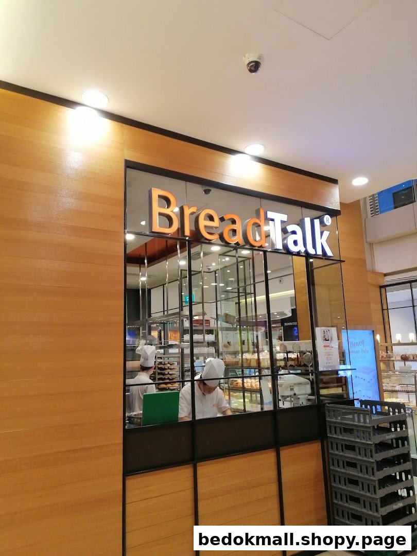Shop front of BreadTalk bakery with staff and products visible through the window.