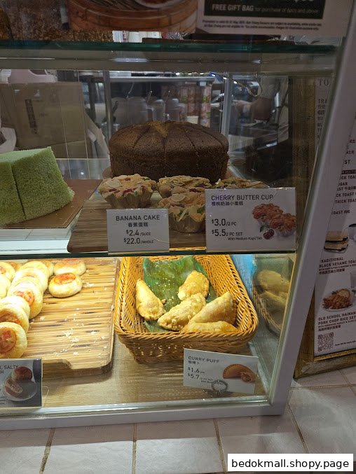 A display case filled with various cakes and pastries with price tags.