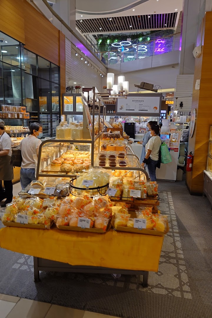 Interior view of a bakery with various baked goods on display and customers.