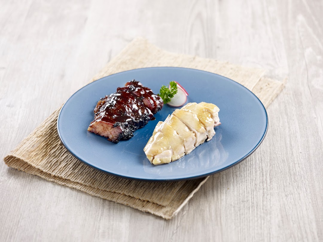 A blue plate with char siew and chicken on a wooden table.