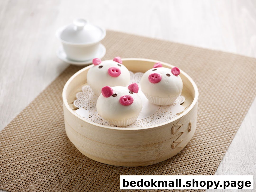 Three pig-shaped buns in a bamboo steamer with a teacup in the background.