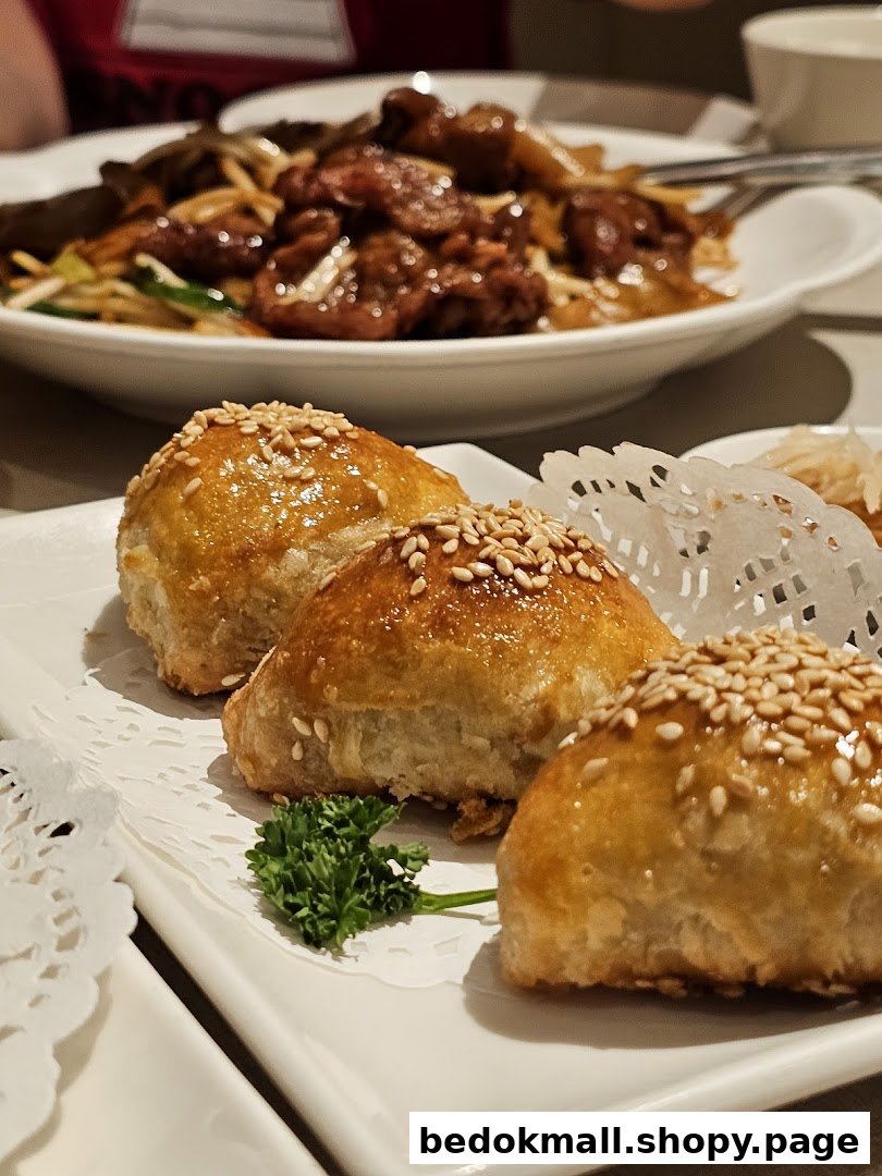 Golden pastries and a noodle dish served on a restaurant table.