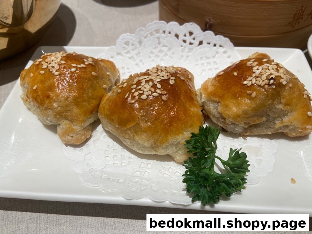 Three golden baked pastries with sesame seeds on a white plate.