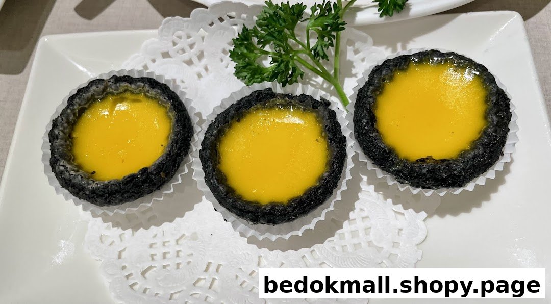 Three black-crusted egg tarts with yellow filling on a white plate.