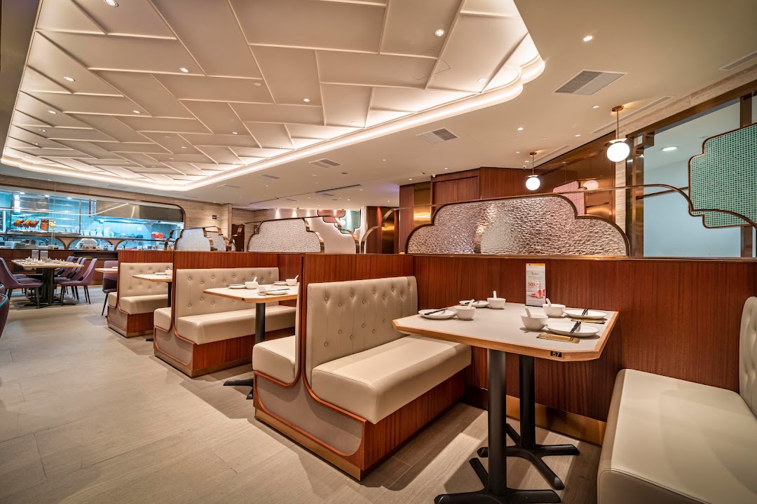 Interior of a modern restaurant with booths and tables, showing kitchen in background.