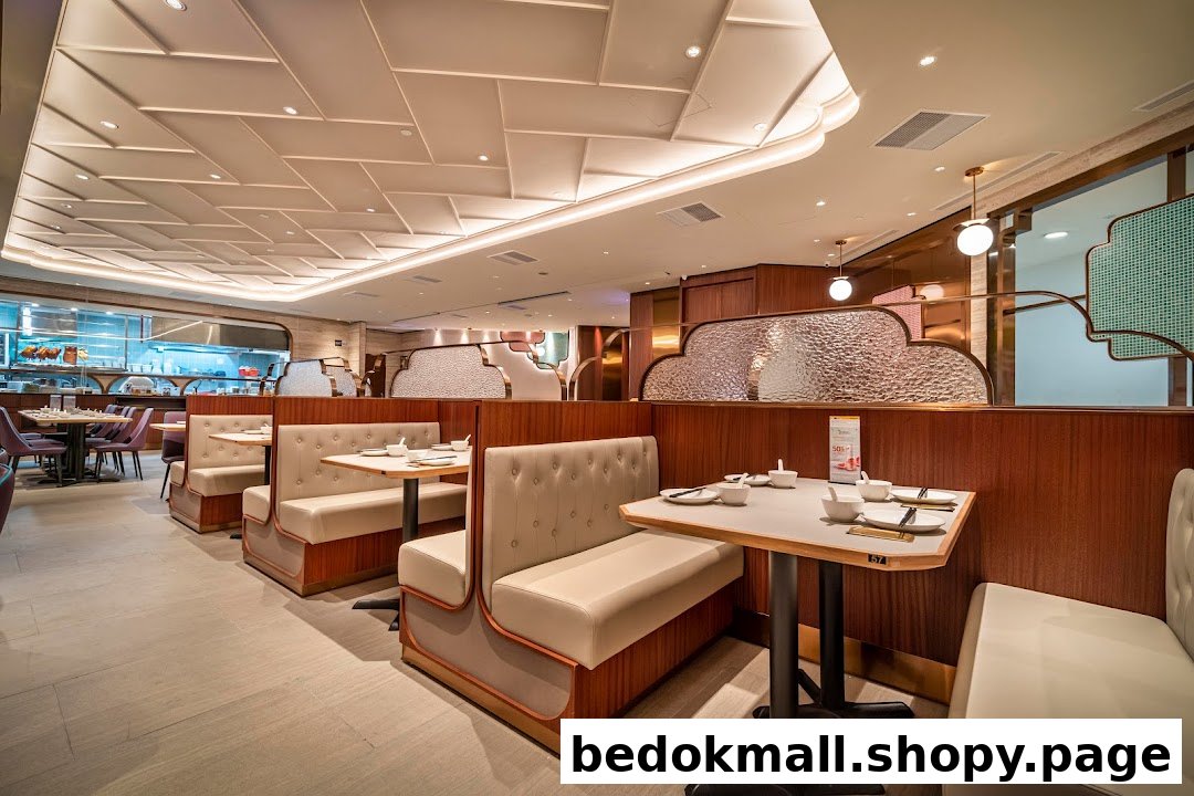 Interior of a modern restaurant with booths and tables, showing kitchen in background.