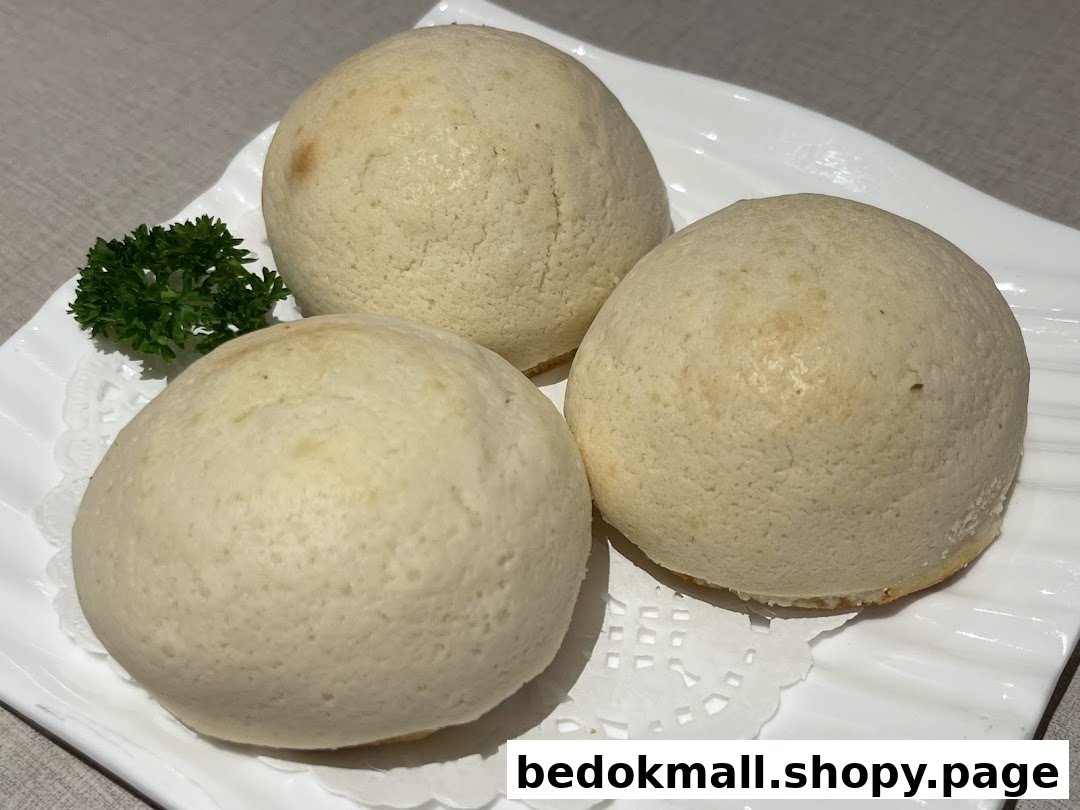 Three light-colored buns on a white plate with a green garnish.