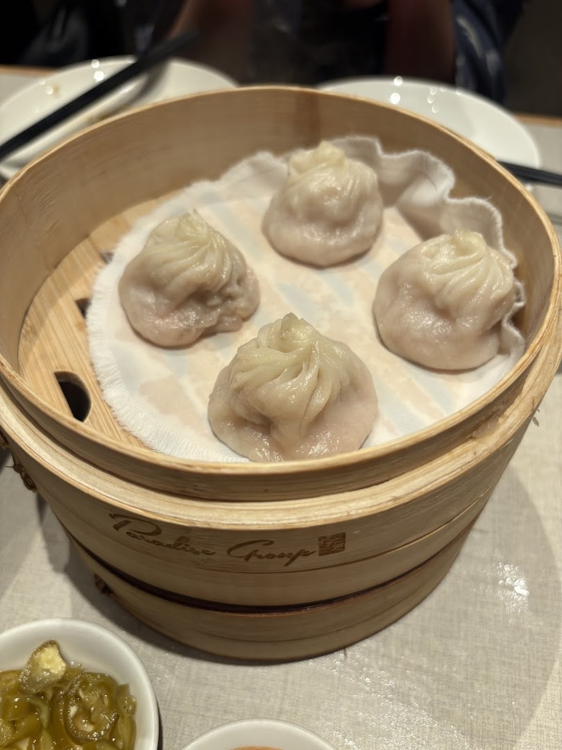 A bamboo steamer filled with five dumplings on a table.