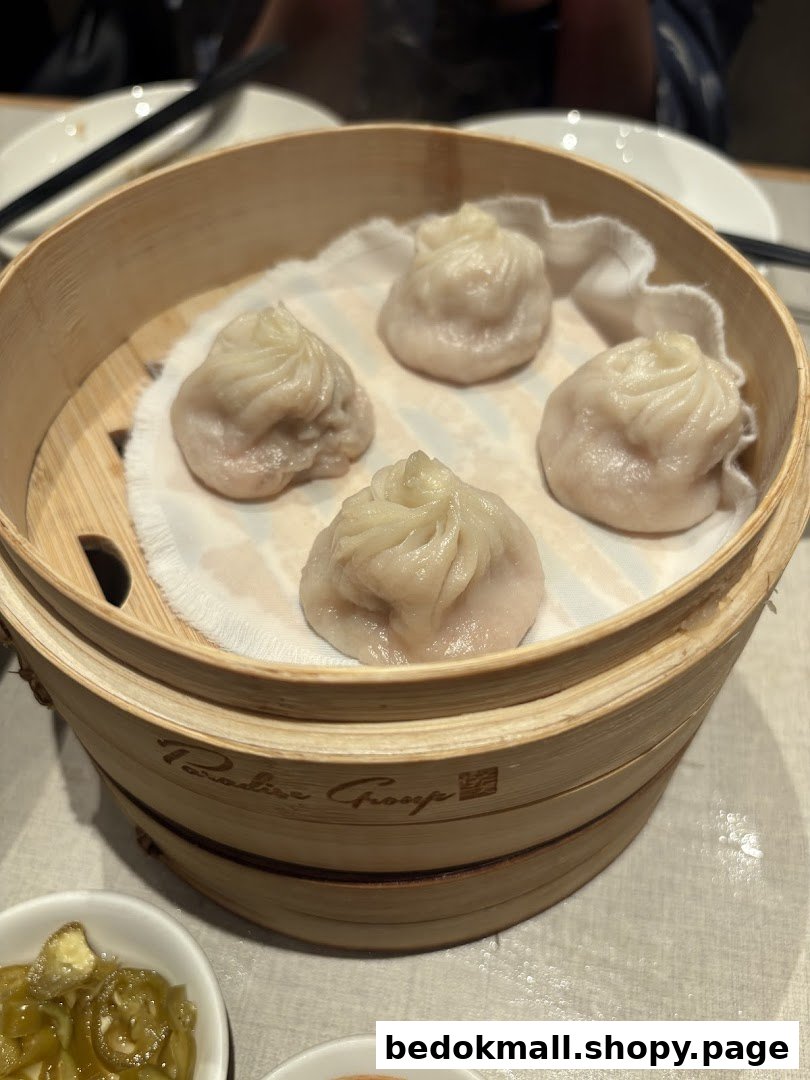 A bamboo steamer filled with five dumplings on a table.