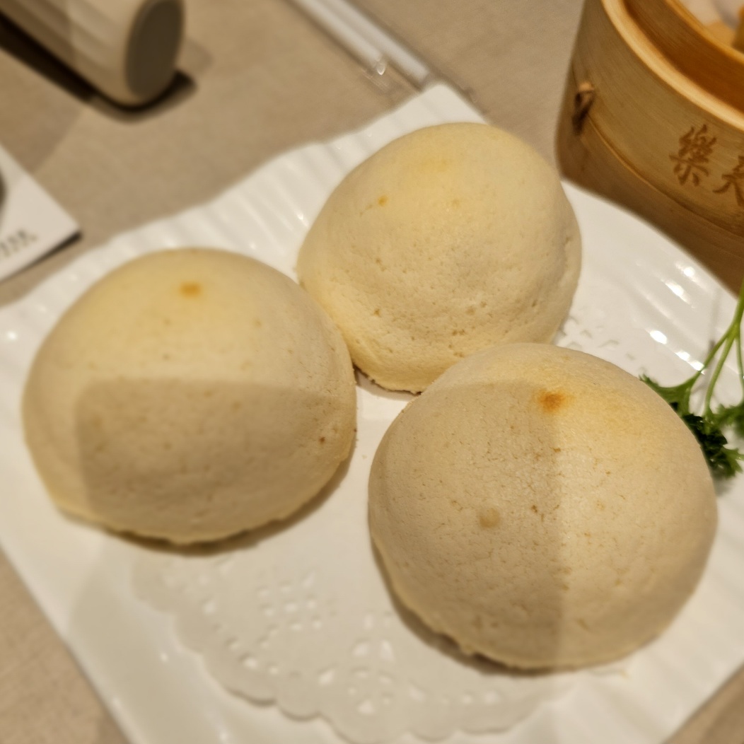 Three light-colored buns are served on a white plate.