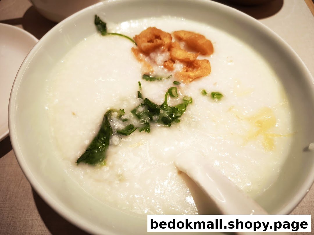 Close-up of a bowl of congee with fried dough and greens.