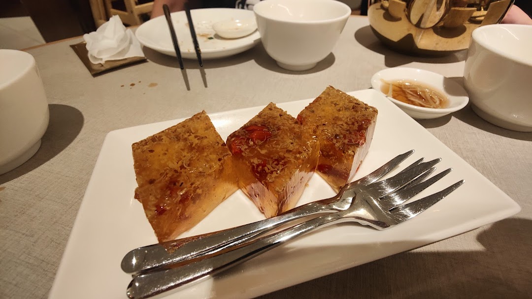 Three pieces of dessert with forks on a white plate at a restaurant table.