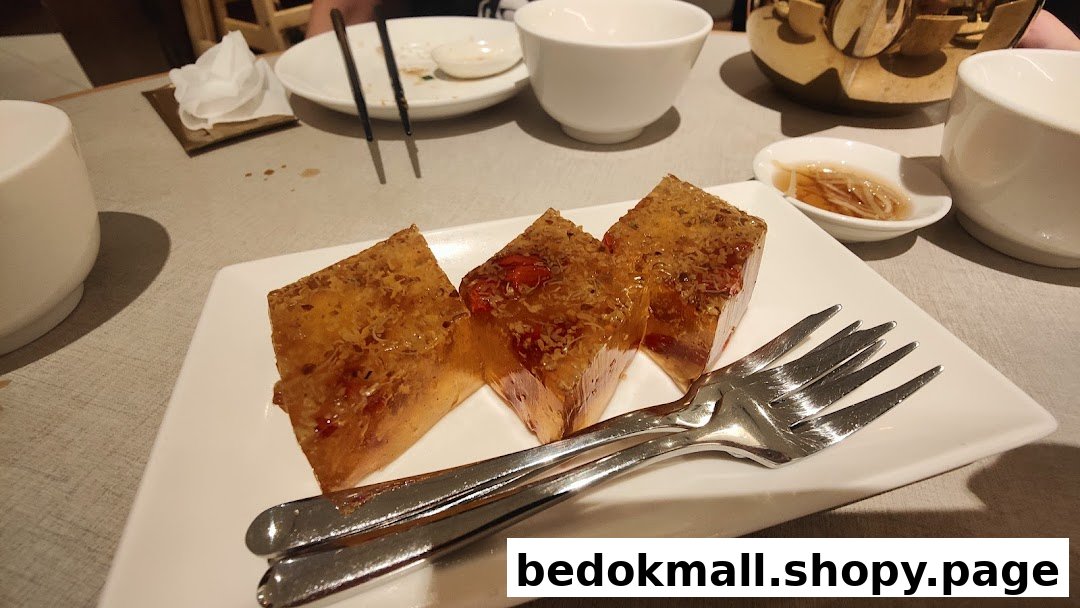 Three pieces of dessert with forks on a white plate at a restaurant table.