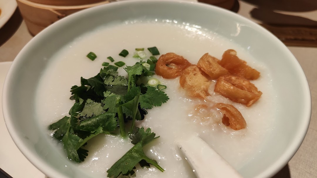 A close-up of a bowl of congee with cilantro and fried dough sticks.