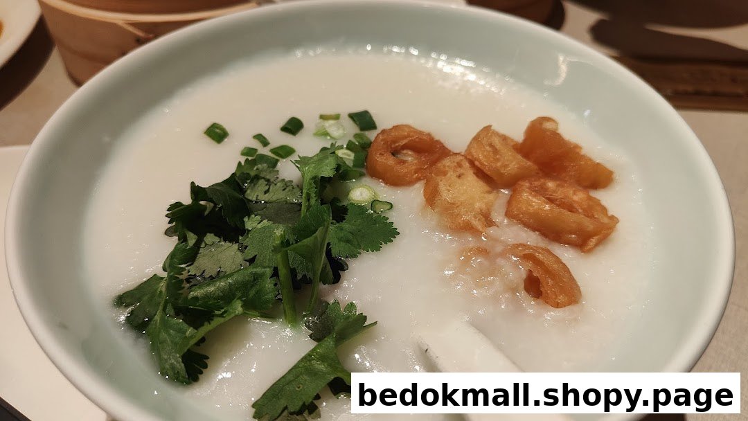 A close-up of a bowl of congee with cilantro and fried dough sticks.