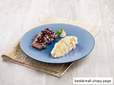 A blue plate with char siu and poached chicken on a wooden table.