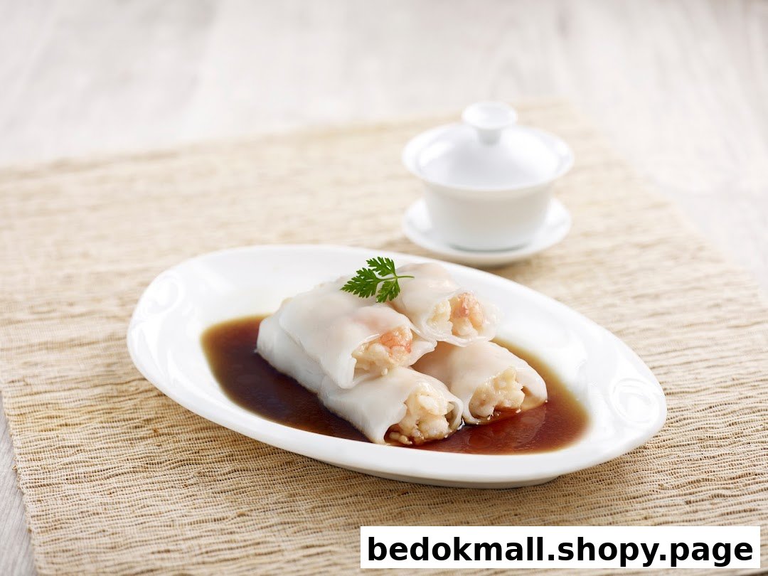 Plate of shrimp rice rolls in sauce with a teacup in the background.