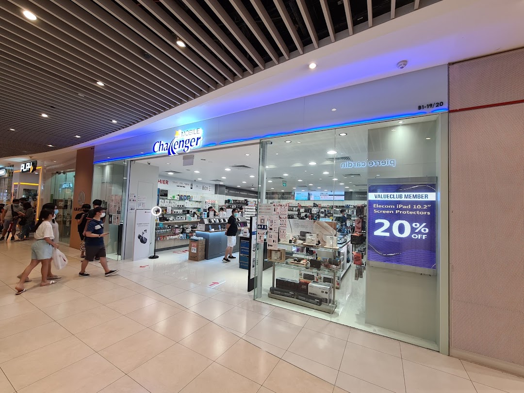 The image shows the glass shop front of Challenger electronics store with people walking by.