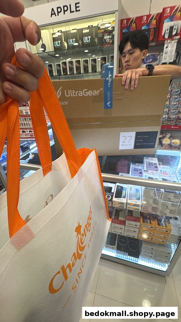 A person holding a Challenger bag inside an electronics store with products and staff.